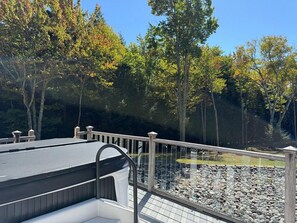 A rooftop deck with a railing overlooking a rocky landscape and trees.