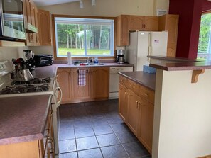 A kitchen with wooden cabinets, a gas stove, a coffee maker, and a refrigerator.