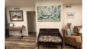A living room with a wooden bench, a framed picture, a large floral artwork, and a 'together' sign. - Coffee Pot Rock Views! Equipped with an Electric Vehicle charger. (Sedona)