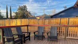 A wooden deck with black chairs and a red railing. - Coffee Pot Rock Views! Equipped with an Electric Vehicle charger. (Sedona)
