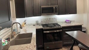 A modern kitchen with dark cabinets, a microwave, a gas stove, and a sink. - Coffee Pot Rock Views! Equipped with an Electric Vehicle charger. (Sedona)