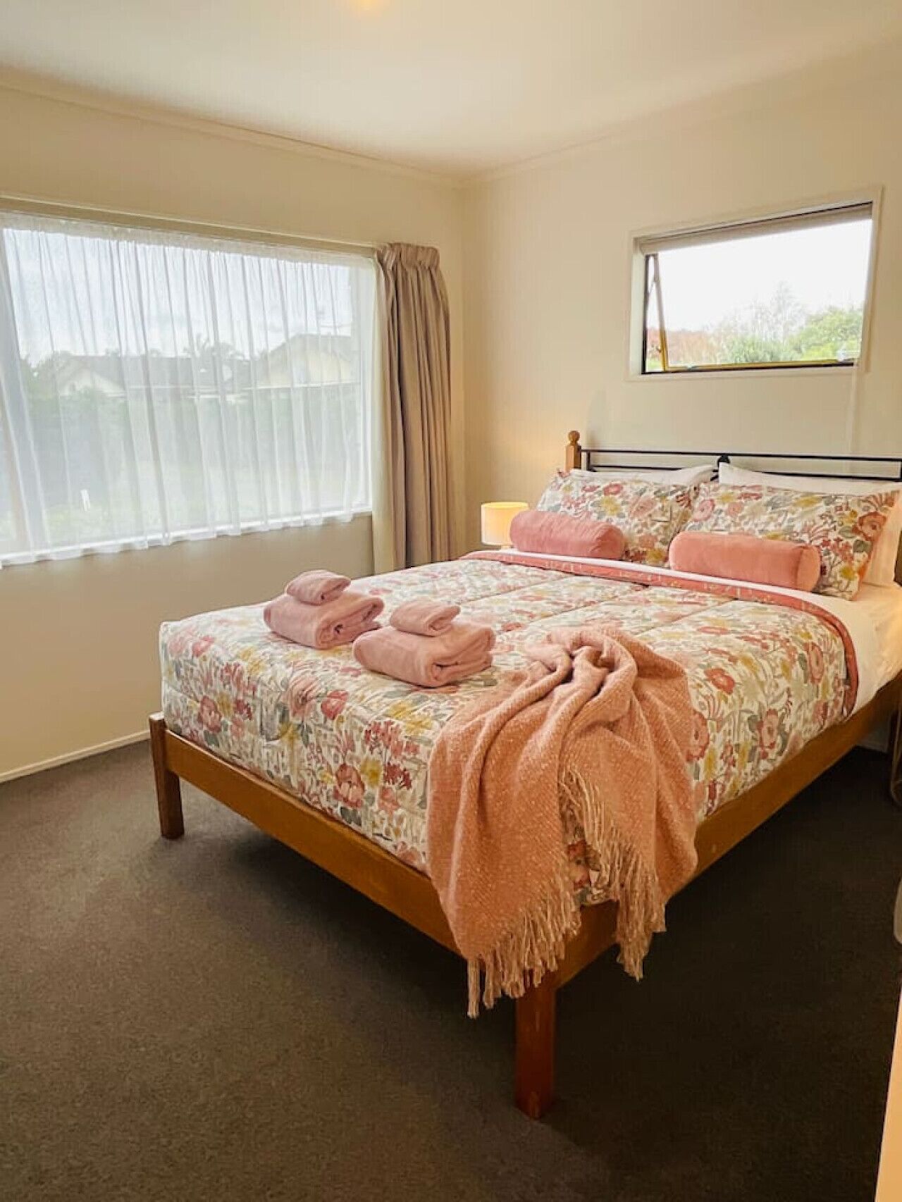 Un dormitorio con una cama, una ventana con cortinas y una lámpara de noche.