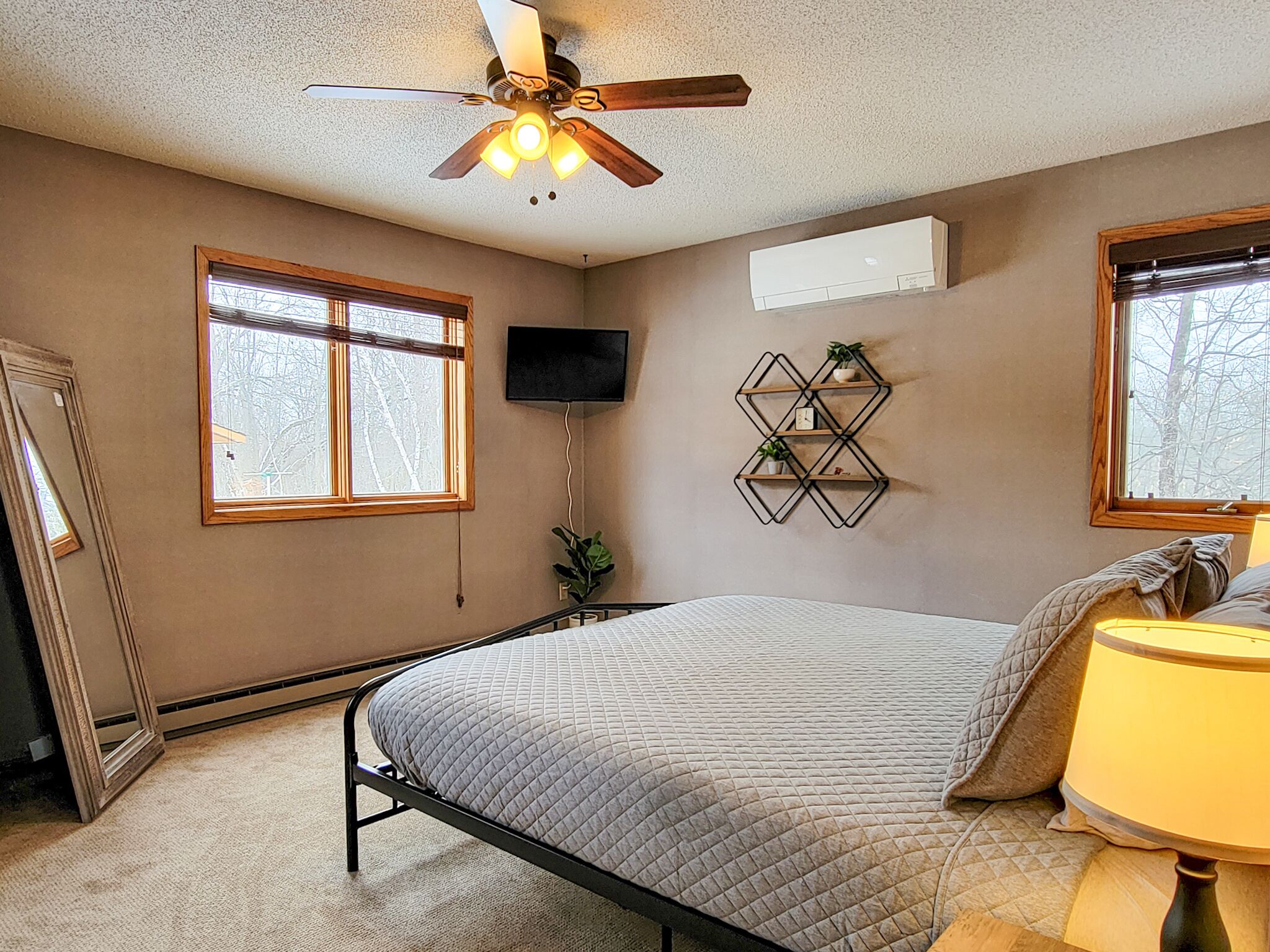 Un dormitorio con cama, ventilador de techo, televisor y ventana.