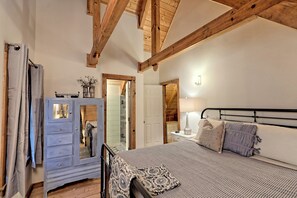 Um quarto com cama, cômoda e mesa de cabeceira.