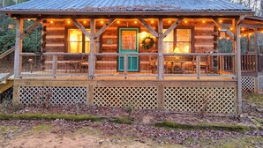 Un rustico chalet con un portico coperto, ringhiera in legno e luci a stringa.