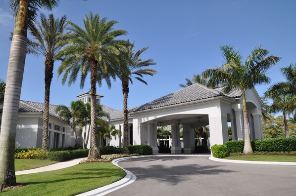 A white building with a covered entrance and palm trees.