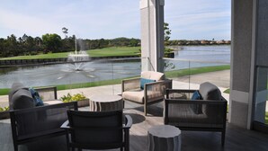 A modern outdoor seating area with a view of a fountain and a golf course. - First-Floor Carriage House at Colonial CC, Renovated Golf Course with Lake View (Fort Myers)