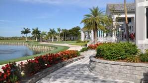 A pathway leading to a building with a pool and palm trees. - First-Floor Carriage House at Colonial CC, Renovated Golf Course with Lake View (Fort Myers)
