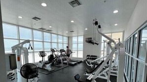 A gym with cardio machines, weightlifting equipment, and large windows offering a view.