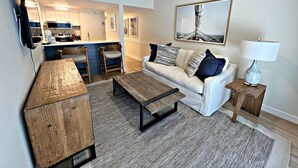 Un salon avec un canapé, une table basse et un téléviseur fixé au mur.