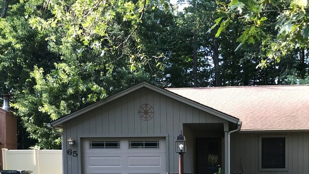 Einbungalow mit Garage, Vorgarten mit Rasen und einem kleinen Garten.