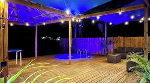 Un patio exterior con terraza de madera, piscina y zonas de estar.