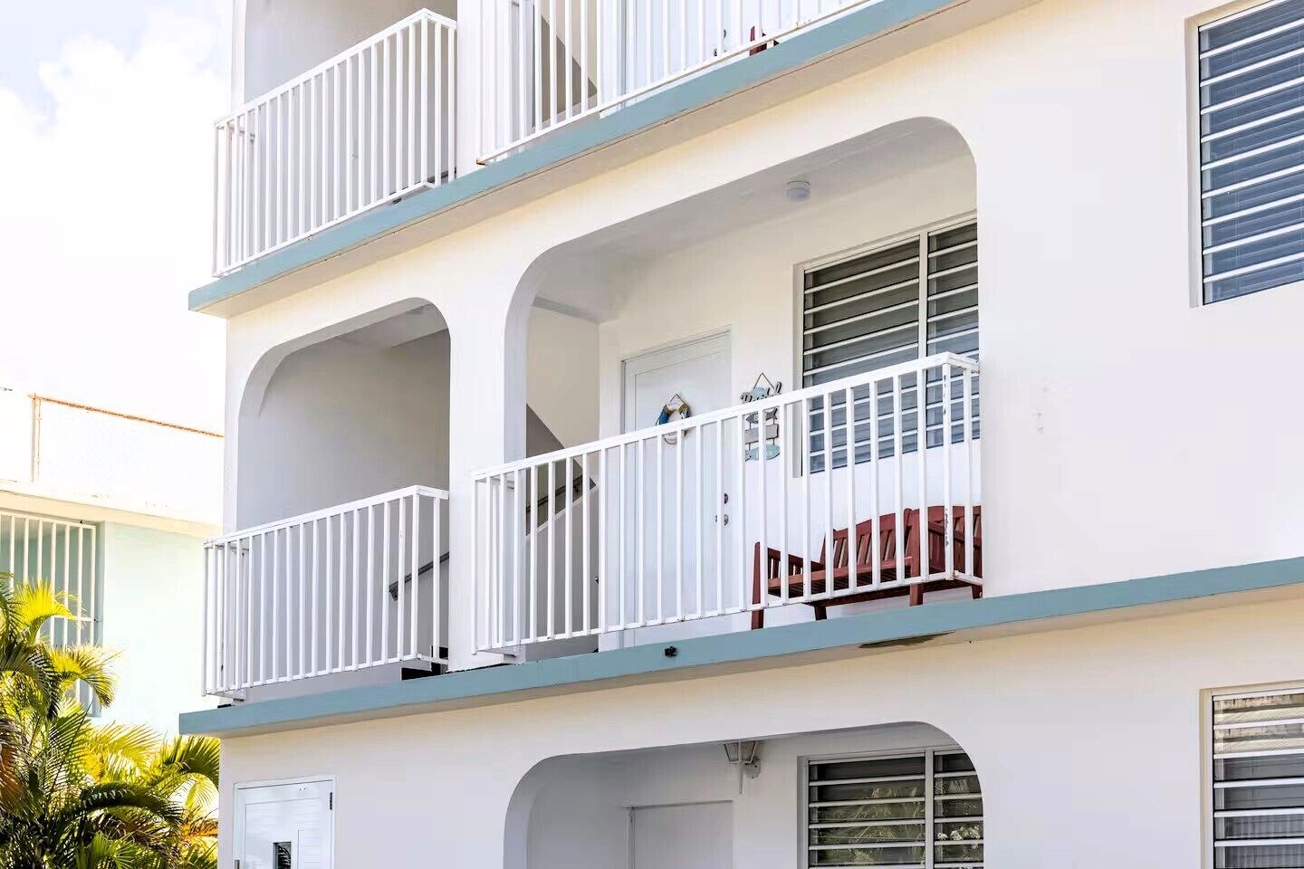 A multi-story building with balconies, a door, and windows.