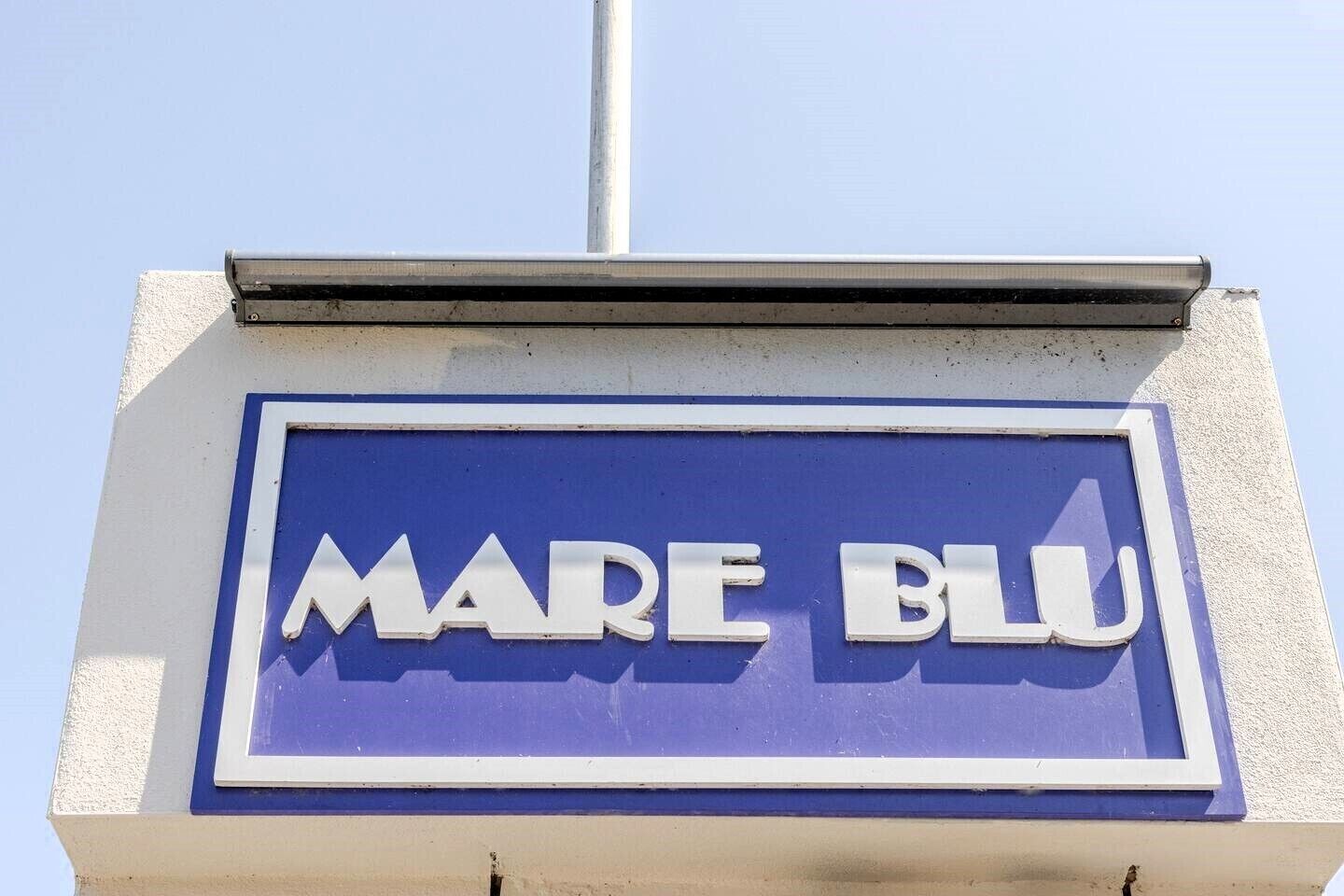 Un letrero azul con el texto 'MARE BLU' en un edificio.