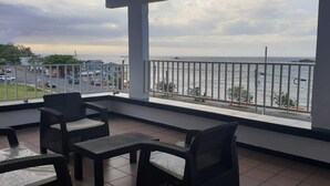 Un balcon doté de meubles en osier et offrant une vue sur la mer.