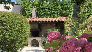 A stone pathway leading to a rustic building with a tiled roof and a stone archway.