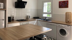 A modern kitchen with a wooden countertop, stainless steel appliances, and a window providing natural light.