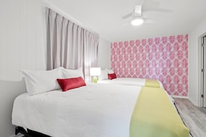 Relax in a stylish room with a large bed, white comforter, and a window with grey curtains.