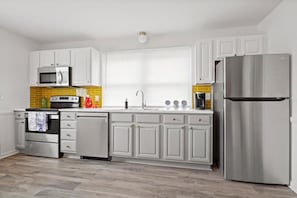 Enjoy cooking in this well-lit kitchen with a refrigerator, oven, and dishwasher.