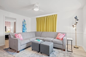 Relax in this stylish living room with a comfortable sofa, two ottomans, and a floor lamp.