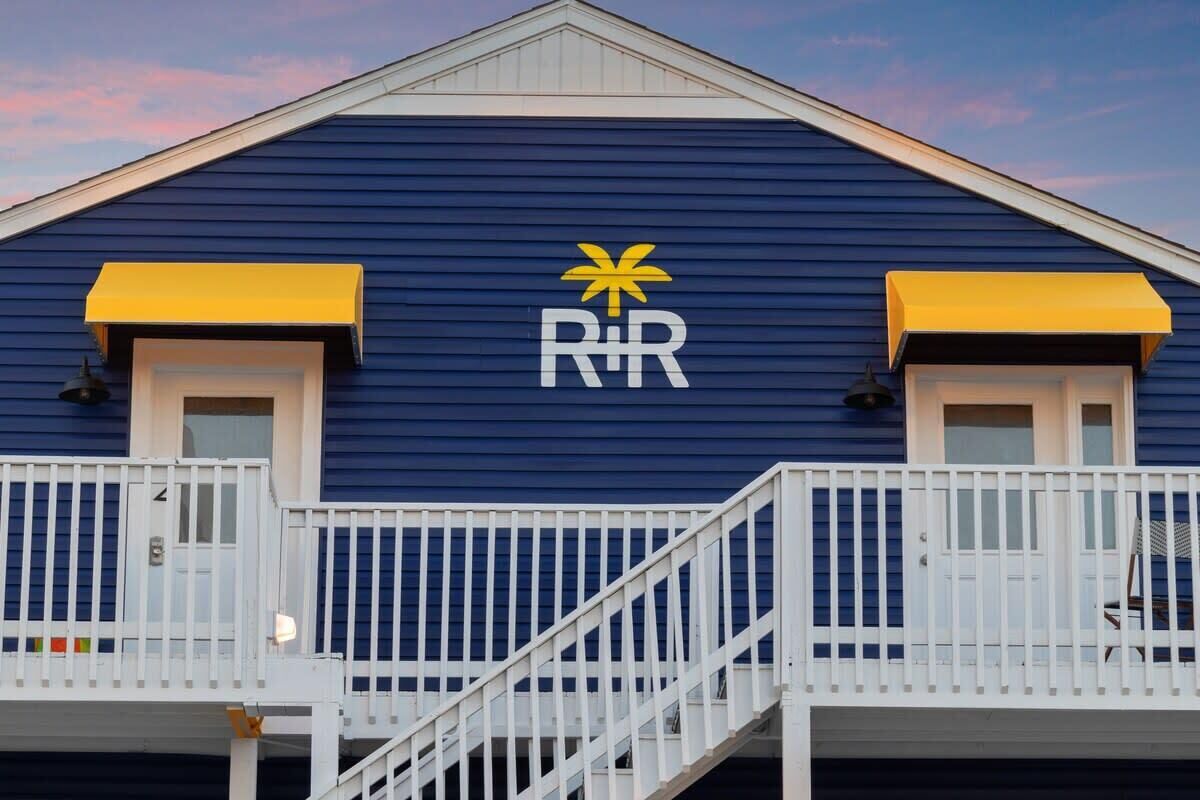 A building with a blue exterior, a white balcony, and a yellow awning.