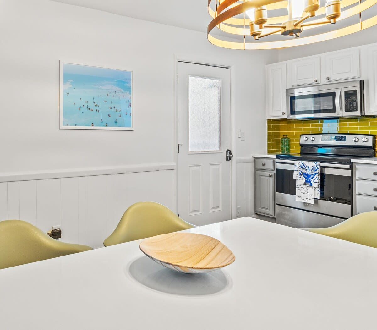 A modern kitchen with white cabinets, a stainless steel stove, and a yellow backsplash.