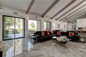 Relax in this stylish living area with a large sofa, glass coffee table, and sliding glass doors leading to an outdoor space.