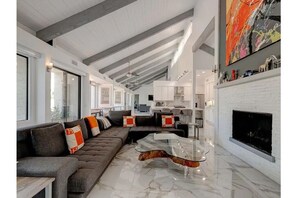 Relax in this stylish living area with a large sectional sofa, glass coffee table, and a cozy fireplace.