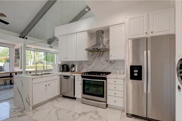 Enjoy cooking in this well-equipped kitchen with an oven, stainless steel range hood, and double-door refrigerator.