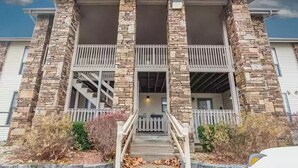 A two-story building with stone columns, a balcony on each floor, and a front porch with steps.
