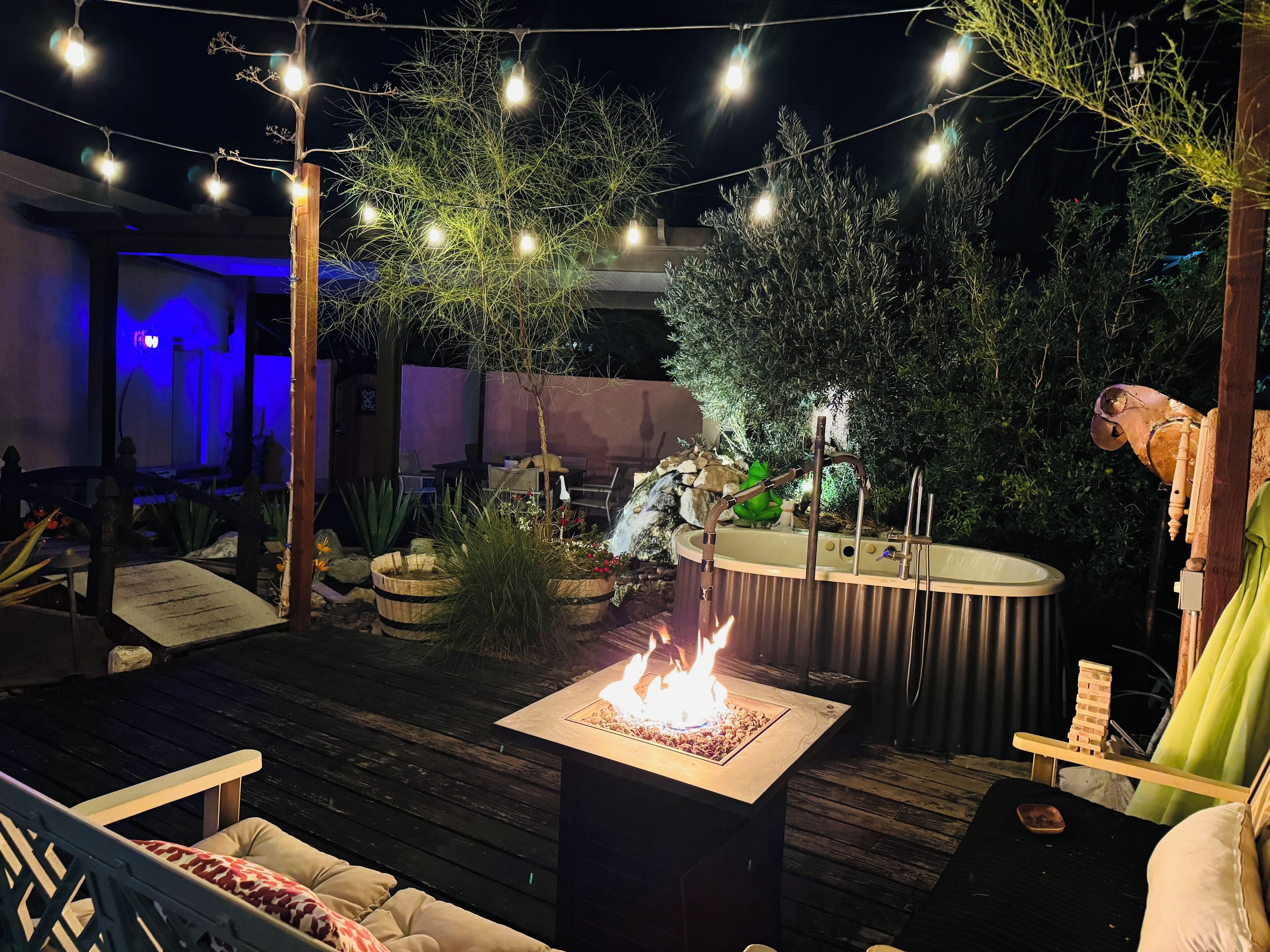 An outdoor patio with a fire feature, seating, and a hot tub.