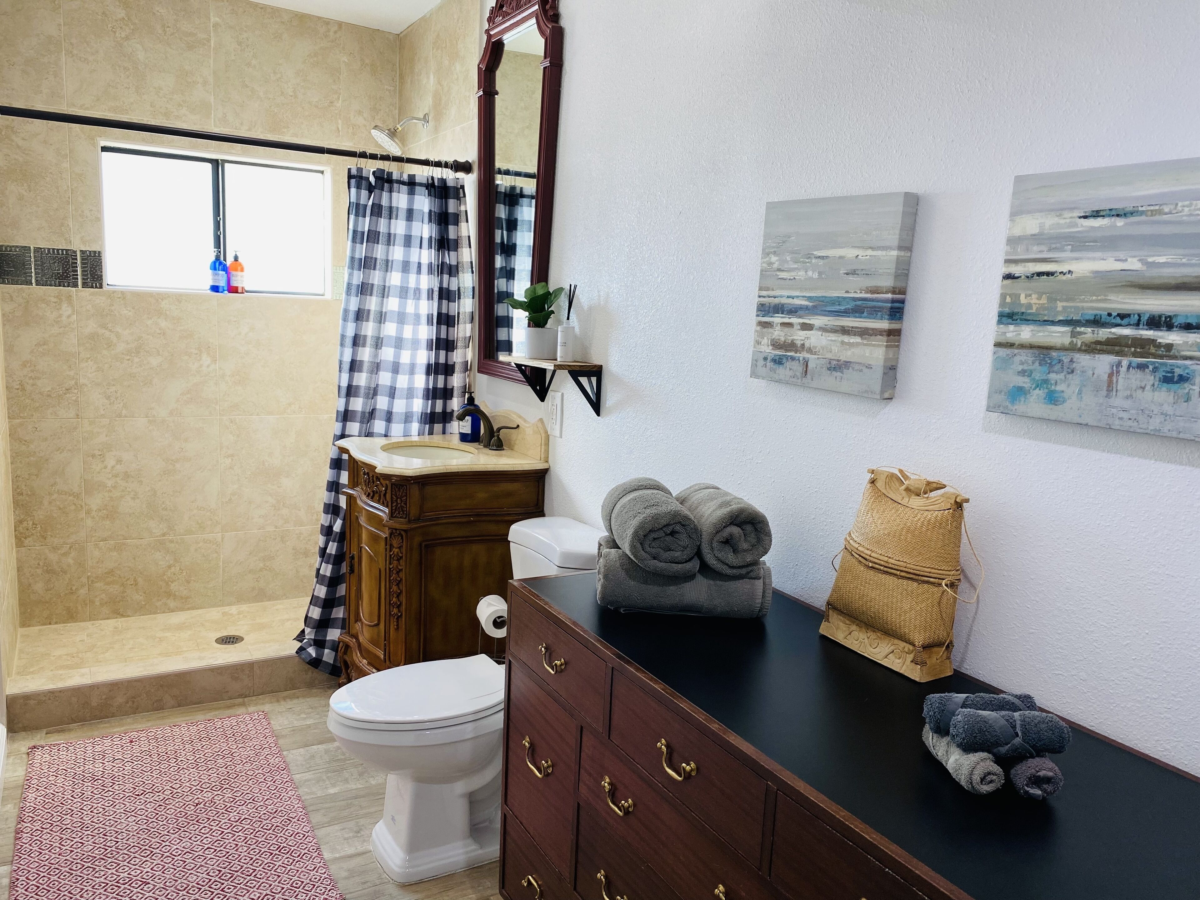A bathroom with a shower, toilet, sink, and a mirror. There are towels and toiletries on the counter.