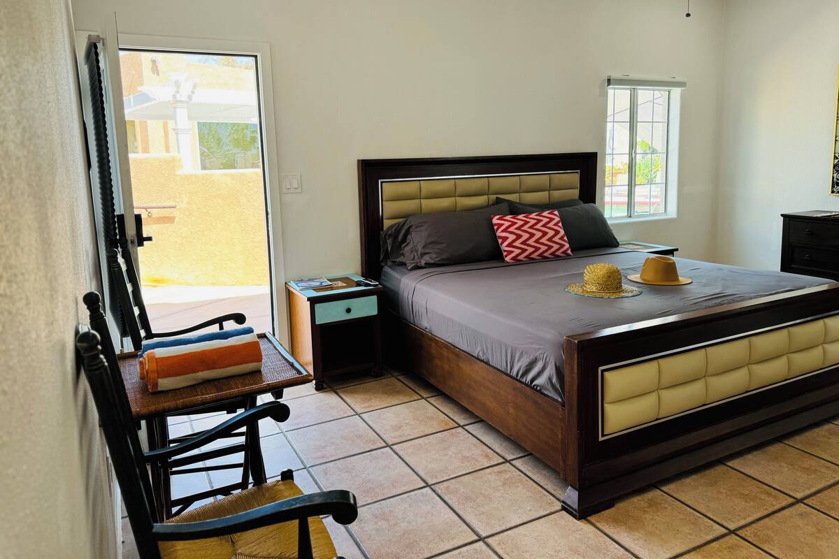 Une chambre à coucher avec un lit, des tables de chevet, une chaise et une fenêtre.
