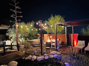 An outdoor patio area with a hot tub, seating, and string lights. - Mi Kasa Hot Springs 420, Adults only, Clothing Optional (Desert Hot Springs)