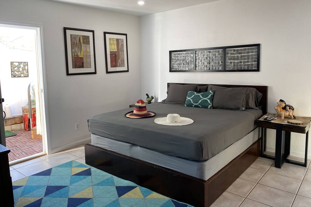 Une chambre à coucher comprenant un lit, une table de chevet et une porte donnant sur un espace extérieur.