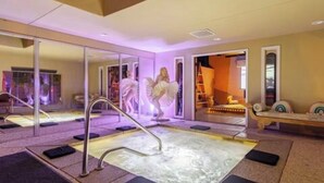 Área de spa com hidromassagem, assentos e um espelho refletindo o espaço.