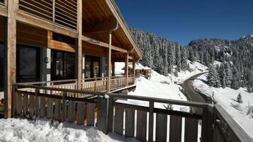 Une cabane en bois dotée d’un balcon donnant sur un sentier de montagne enneigé.