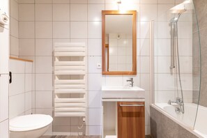 A modern bathroom with a toilet, a white sink, a mirror, and a glass-enclosed shower area. - Residence Les Portes du Grand Massif – Flaine (Araches-la-Frasse)