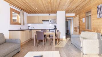 Un interior moderno con techo de madera, una zona de cocina con microondas, una mesa de comedor con sillas y dos sofás.
