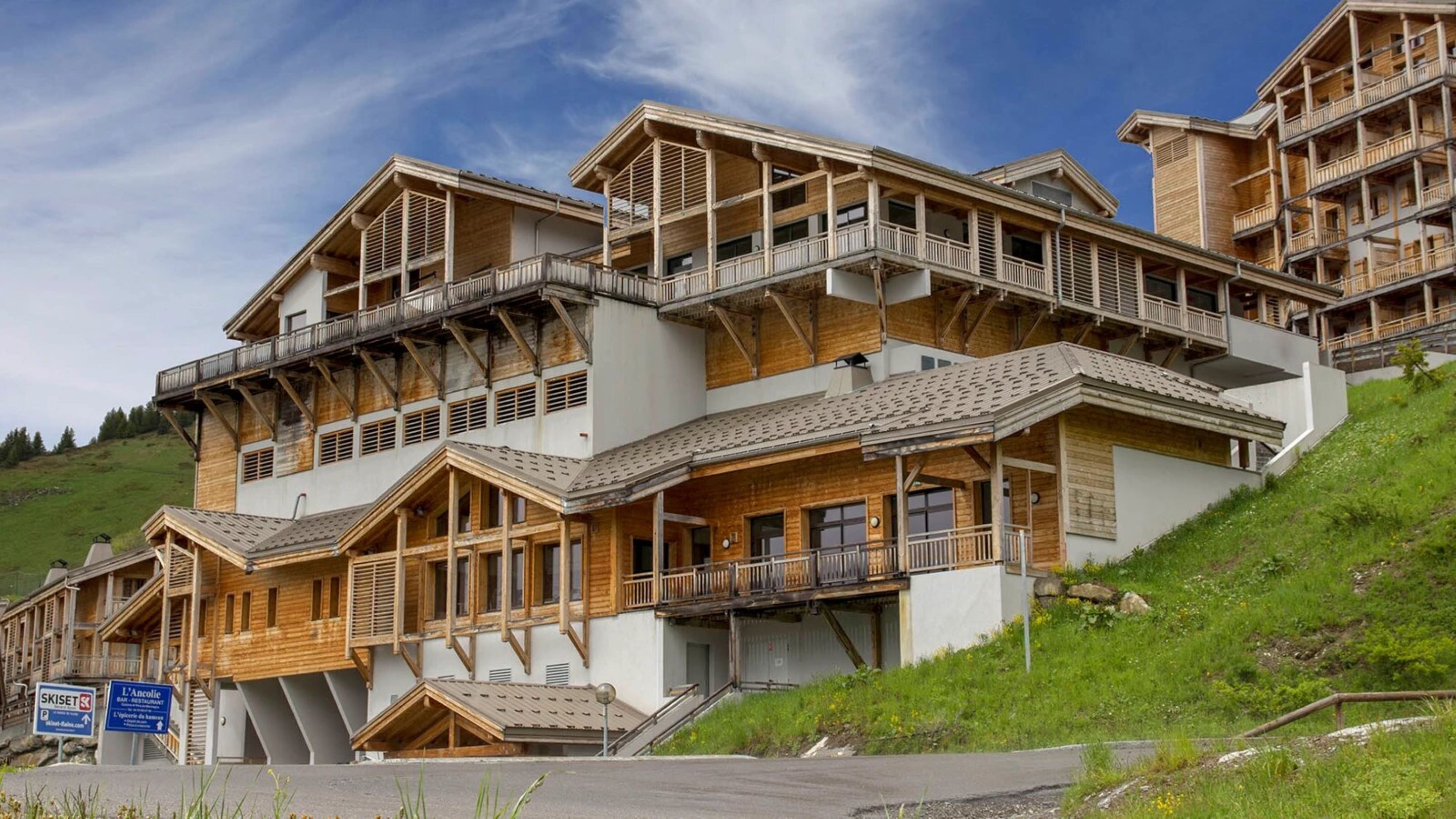 A multi-story chalet with wooden balconies and a ski lift visible in the background.
