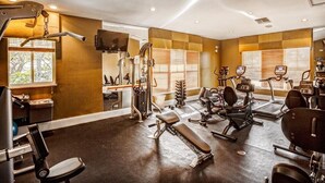 Une salle de sport équipée de divers appareils d’exercice, notamment des tapis de course, des appareils de musculation et un banc.