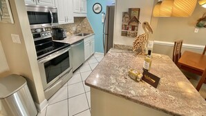 A modern kitchen with white cabinets, stainless steel appliances, and a granite countertop.