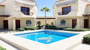 A swimming pool with a turtle design, surrounded by two-story buildings with balconies and a palm tree. - Villa Sonari 4 by Kivoya (Puerto Peñasco)
