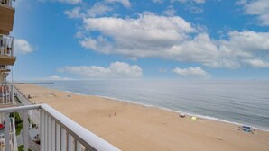 Uitzicht op een strand vanaf een balkon, met een heldere lucht en een zandstrand.