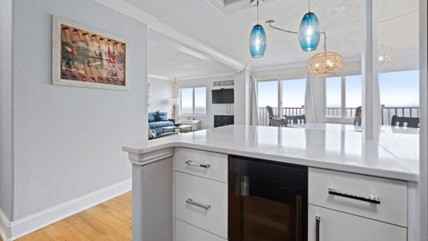 Een moderne keuken met witte kasten, een centraal eiland en hanglampen.