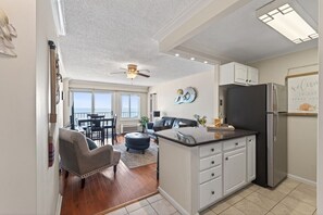 A modern kitchen with a central island, white cabinetry, and a black refrigerator.