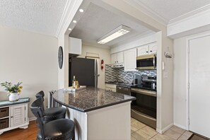 Una cocina moderna con una isla central, electrodomésticos de acero inoxidable y un salpicadero de azulejos.