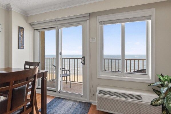A room with a view of the ocean, a dining table with chairs, and a radiator.