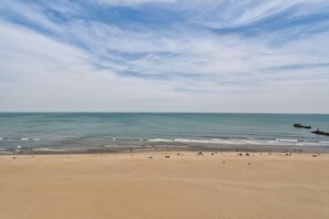A beach with a clear sky, calm sea, and a sandy shore.