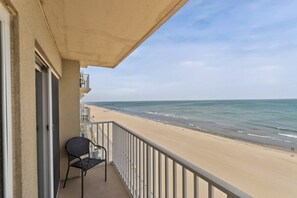 A balcony with a view of a beach and ocean.